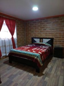 1 dormitorio con 1 cama con pared de ladrillo en Cozy cabin in the countryside Otavalo Learning, en Otavalo