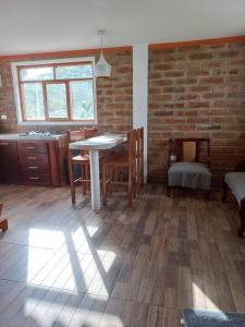 Cette chambre dispose d'une table, de chaises et d'un mur en briques. dans l'établissement Cozy cabin in the countryside Otavalo Learning, à Otavalo