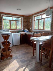 eine Küche mit einem Tisch und einem Herd sowie einige Fenster in der Unterkunft Cozy cabin in the countryside Otavalo Learning in Otavalo