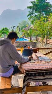 寧平的住宿－Trang An Quynh Trang Happy Homestay & Garden，坐在野餐桌旁的长凳上的人