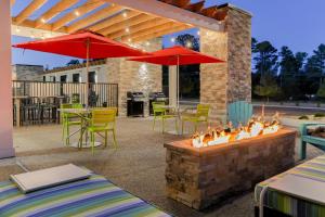 a patio with a fire pit with chairs and umbrellas at Home2 Suites By Hilton Alcoa Knoxville Airport in Alcoa