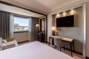 a hotel room with a bed and a desk and a television at NH Collection A Coruña Finisterre in A Coruña