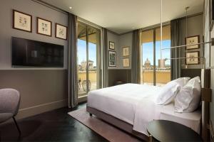 a bedroom with a bed and a tv and windows at Radisson Collection Hotel, Roma Antica in Rome