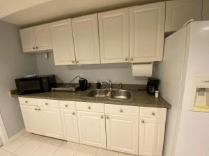 una cucina con armadi bianchi, lavandino e forno a microonde di Fully furnished basement studio apartment a Mississauga