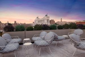 un patio all'ultimo piano con sedie, tavoli e una città di Radisson Collection Hotel, Roma Antica a Roma