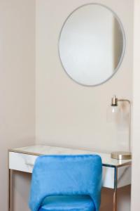 a blue chair sitting next to a desk with a mirror at Beautiful Irving two bedroom apartment in Philadelphia