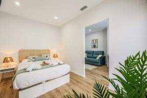 a white bedroom with a bed and a blue couch at Luxe apartments Madrid Rio by RentitUP in Madrid