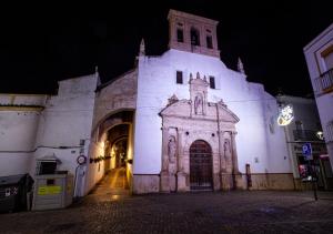 a large white building with a clock tower at night at Encanto Urbano: Piso céntrico totalmente equipado in Lebrija