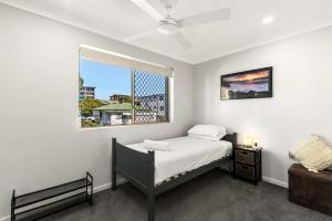 Charming 3-bed Apartment near Local Shops في بريزبين: غرفة نوم بسرير ونافذة