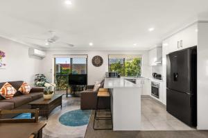 eine Küche und ein Wohnzimmer mit einem Sofa und einem Tisch in der Unterkunft Charming 3-bed Apartment near Local Shops in Brisbane