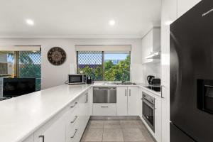 eine Küche mit weißen Schränken und einem großen Fenster in der Unterkunft Charming 3-bed Apartment near Local Shops in Brisbane