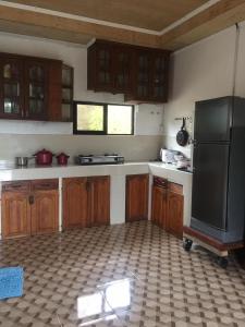 a kitchen with wooden cabinets and a black refrigerator at Oslob Hilltop Transient House in Cañang