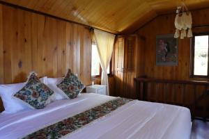 1 dormitorio con 1 cama blanca y paredes de madera en Nhà Chim Ri - Homestay Cafe Đà Lạt, en Da Lat