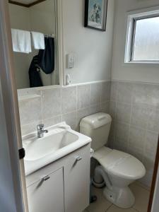 a bathroom with a toilet and a sink and a mirror at Batemans Bay Holiday Park & Hostel in Batemans Bay