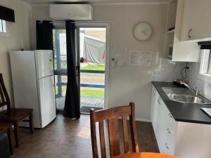 uma cozinha com um frigorífico, uma mesa e cadeiras em Batemans Bay Holiday Park & Hostel em Batemans Bay