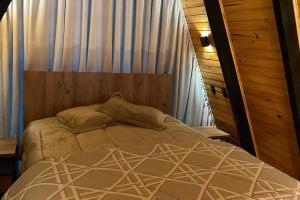 a bed in a bedroom with a curtain and a bedskirtspectspectspectspects at Winter Valley Cabins in São Joaquim