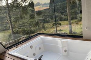 a bath tub in a bathroom with a large window at Winter Valley Cabins in São Joaquim +40 photos