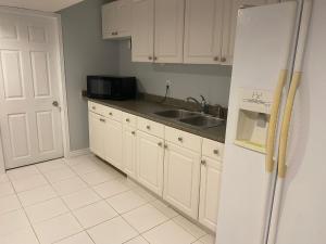 una cucina con armadi bianchi, lavandino e frigorifero di Fully furnished basement studio apartment a Mississauga