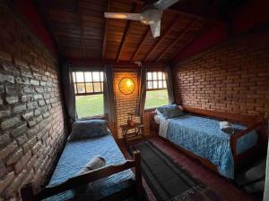 Zimmer mit 2 Betten und Ziegelwand in der Unterkunft Rancho encontro dos sonhos in Carrancas