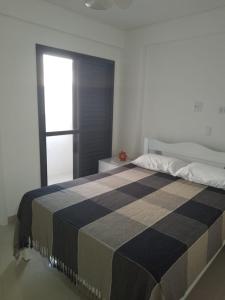 a bedroom with a bed with a checkered blanket at Praia Mansa Caiobá 3 quartos in Matinhos