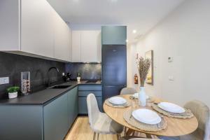 cocina con mesa de madera y cocina con armarios azules en Luxe apartments Madrid Rio by RentitUP, en Madrid