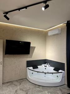 a bathroom with a bath tub and a tv on the wall at Falco Boutique Home with Jacuzzi in Naples