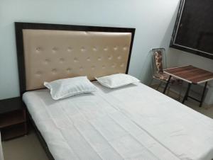 een bed met 2 kussens en een stoel in een kamer bij Mahendra home stay in Faizābād