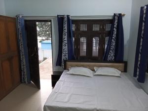 een slaapkamer met een bed met blauwe gordijnen bij Mahendra home stay in Faizābād