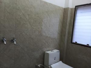 een badkamer met een douche, een toilet en een raam bij Mahendra home stay in Faizābād