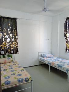 twee bedden in een kleine kamer met gordijnen bij Homestay Indrawasih with 2 Bedroom in Perai