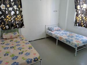 twee bedden in een kamer met bloemen op de lakens bij Homestay Indrawasih with 2 Bedroom in Perai