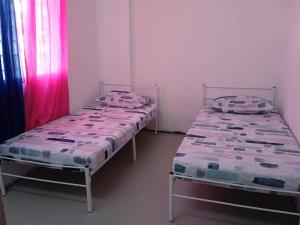 twee bedden in een kamer met roze gordijnen bij Homestay Indrawasih with 2 Bedroom in Perai