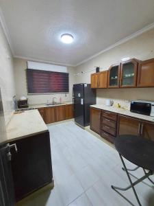 uma cozinha com armários de madeira e um frigorífico preto em Elegant apartments for rent. em Amã