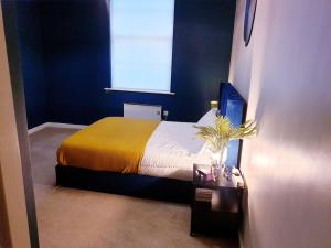 a bedroom with a bed with a yellow blanket and a window at Kelham Island - City Centre - Stylish - 2 BD - Free On-street Parking - Netflix - Fast WiFi in Sheffield