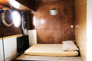 a small bed in a room with a wall at Belle péniche romantique à Paris in Boulogne-Billancourt