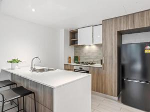 a kitchen with a sink and a refrigerator at Newstead Modern 2-storey Apartment - Q Stay in Brisbane