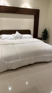 ein weißes Bett mit einem Kopfteil aus Holz im Schlafzimmer in der Unterkunft شقة مفروشة بدخول ذاتي in Al Kharj