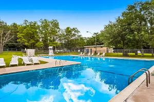 a swimming pool with white chairs and trees at House in the Woods in Albrightsville