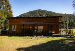 una pequeña casa de madera con una montaña en el fondo en Villa Vida. Sua cabana entre Urubici e São Joaquim - Serra Catarinense, en São Joaquim