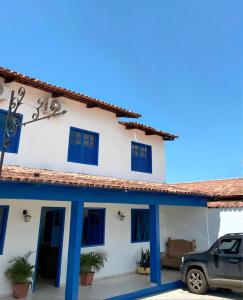 a house with blue windows and a car parked in front at Pousada JK in Pirenópolis