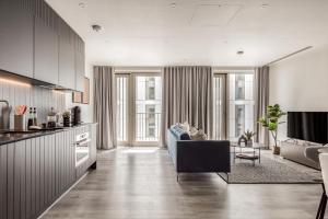 a living room with a couch and a kitchen at Urban Rest Stratford Apartments in London