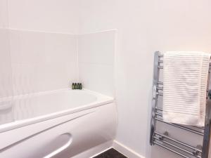 a white bathroom with a tub and a towel rack at Kelham Island - City Centre - Stylish - 2 BD - Free On-street Parking - Netflix - Fast WiFi in Sheffield