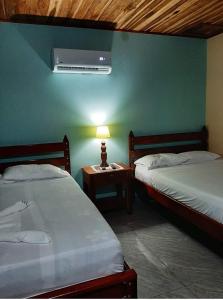 a room with two beds and a lamp on a table at Cabinas El Pilón Río Celeste in San Rafael