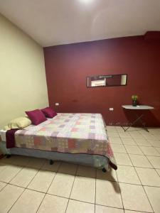 ein Schlafzimmer mit einem Bett und einer roten Wand in der Unterkunft Habitación Privada Andrea, en la Isla in Flores