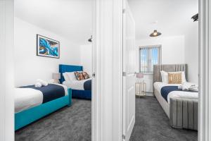 a room with two beds and a door with two chairs at CALIBER STAYS® Serviced Homes Collection - Serviced Houses Derby City Centre - Ideal Contractors & Family Choice in Derby
