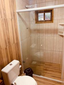 a bathroom with a toilet and a glass shower at Casa de aluguel praia do rosa in Garopaba +16 photos