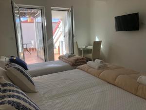 Duas camas num quarto com uma televisão e uma mesa em Thalassa Suite & Spa em Reggio di Calabria