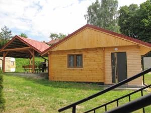 a small wooden cabin with a porch at Small holiday home, right on the lake, Ryn in Ryn