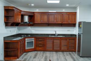 a kitchen with wooden cabinets and a sink and a refrigerator at HAMPTONS Apartments in Phnom Penh