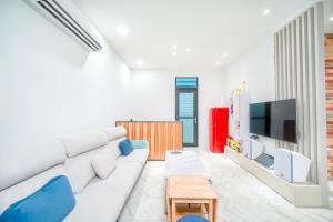 ein Wohnzimmer mit einem weißen Sofa und einem TV in der Unterkunft Penghu I Stay II in Magong